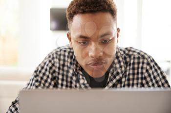 Close up of black male teenager using a laptop computer, front view