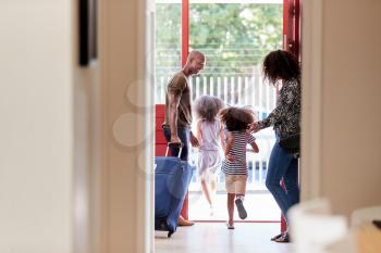 Family Standing By Front Door With Suitcase About To Leave For Vacation