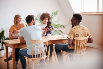Two Families With Babies Meeting And Talking Around Table On Play Date At Home