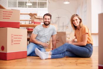 Portrait Of Couple Celebrating Moving Into New Home Drinking Champagne