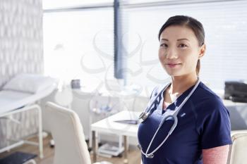 Portrait Of Smiling Female Doctor With Stethoscope Standing By Desk In Office