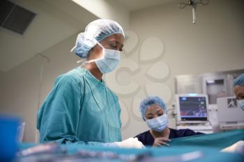 Female Surgical Team Working On Patient In Hospital Operating Theatre