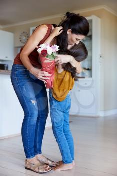 Daughter embracing her mother after giving her flowers on her birthday, full length, vertical