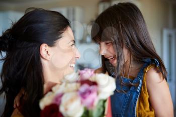 Young white girl giving her mother flowers as a gift on her birthday, close up, selective focus