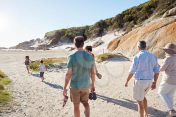 Back view of three generation white family exploring together on a sunny beach