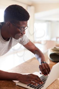 Millennial African American man checking fitness app on smartwatch using laptop at home after gym, vertical