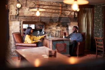 Couple Meeting For Lunchtime Drinks In Traditional English Pub