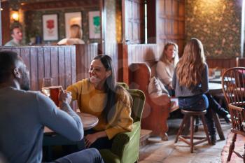 Couple Meeting For Lunchtime Drinks In Traditional English Pub Making A Toast