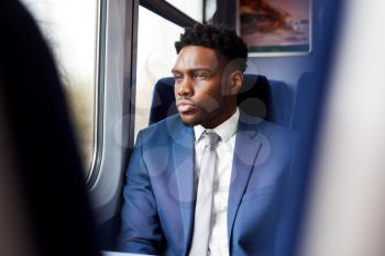 Businessman Sitting In Train Commuting To Work Looking Out Of Window