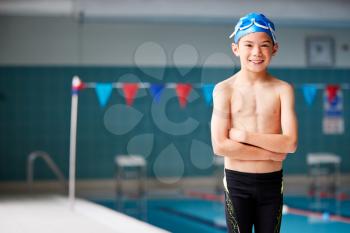 Portrait Of Boy Standing By Edge Of Swimming Pool Ready For Lesson