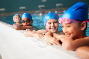 Group Of Children In Water At Edge Of Pool Waiting For Swimming Lesson