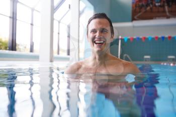 Portrait Of Male Swimmer Warming Up In Swimming Pool