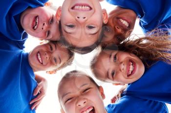 Low Angle View Looking Up Into Faces Of Children In Huddle On Sports Day