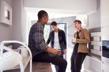 Group Of Male College Students In Shared House With Hot Drinks In Kitchen Hanging Out Together