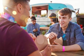 Group Of Friends Eating Takeaway Food From Truck At  Outdoor Music Festival