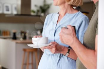 Close Up Of Senior Couple Standing At Home In Kitchen Drinking Morning Coffee Together