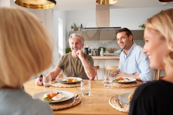 Family With Senior Parents And Adult Offspring Eating Brunch Around Table At Home Together