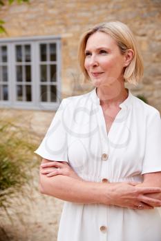 Portrait Of Mature Woman Standing Outside Front Door Of Home