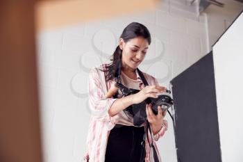 Female Crew Member On Video Film Set Operating Wireless Follow Focus Module In White Studio