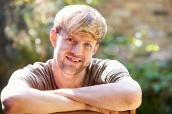 Portrait Of Smiling Man At Home In Garden Against Flaring Sun