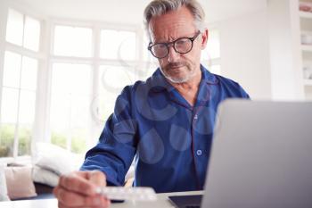 Mature Man At Home Looking Up Information About Medication Online Using Laptop