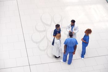 Overhead View Of Medical Staff Having Informal Meeting In Lobby Of Modern Hospital Building