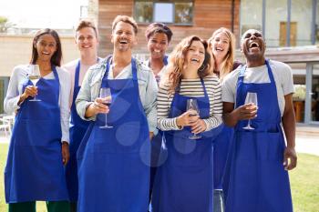 Group Portrait Of Men And Women Attending Cookery Class Relaxing Outdoors With Glass Of Wine