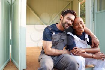 Portrait Of Couple Taking A Break From Building Outdoor Summerhouse In Garden