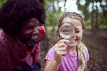 Girl With Male Team Leader At Outdoor Activity Camp Studying Forest Nature With Magnifying Glass