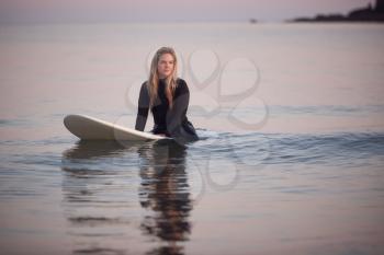 Woman Wearing Wetsuit Sitting And Floating On Surfboard On Calm  Sea