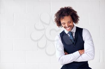 Confident Young Businessman Wearing Suit Standing Against White Studio Wall