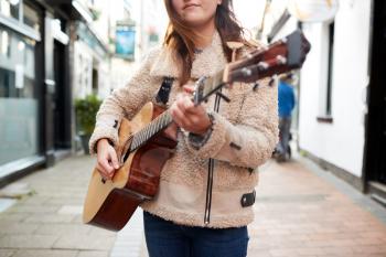 Close Up Of  Female Musician Busking Playing Acoustic Guitar  Outdoors In Street