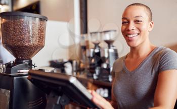 Portrait Of Female Coffee Shop Owner Standing At Sales Desk