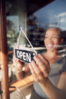 Female Owner Of Start Up Coffee Shop Or Restaurant Turning Round Open Sign On Door