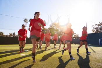 Womens Football Team Run Whilst Training For Soccer Match On Outdoor Astro Turf Pitch