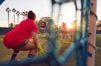 View Through Goal Net Of Womens Football Team Playing Soccer Match