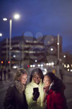 Group Of Female Friends On City Street At Night Ordering Taxi Using Mobile Phone App