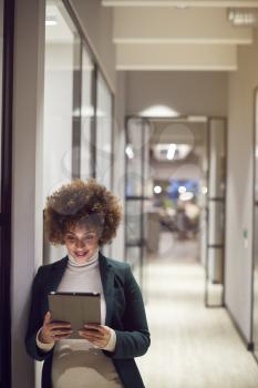 Evening Shot Of Pregnant Businesswoman Standing In Corridor Of Modern Office Using Digital Tablet