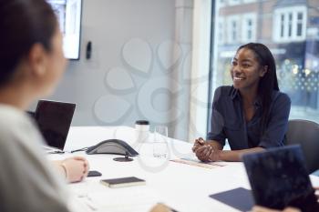 Smiling African American Businesswoman Sitting At Table In Office  Meeting Room