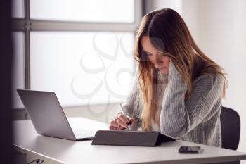 Businesswoman Working From Home Drawing On Digital Tablet Using Stylus Pen