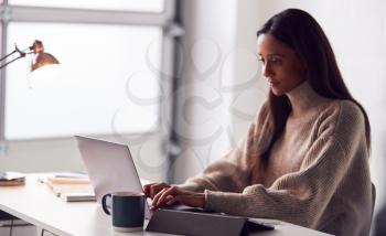 Businesswoman Working On Laptop At Desk In Modern Office
