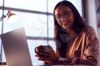 Portrait Of Businesswoman Working On Laptop At Desk In Modern Office