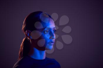 Studio Profile Shot Of Woman With Face Illuminated By Blue Light