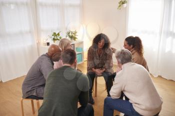 Group Consoling Woman Speaking At Support Group Meeting For Mental Health Or Dependency Issues