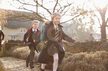 Children Wearing School Uniform  Returning Home From School Running Down Path