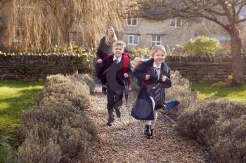 Mother Returning Home From School With Children Wearing School Uniform Running Down Path