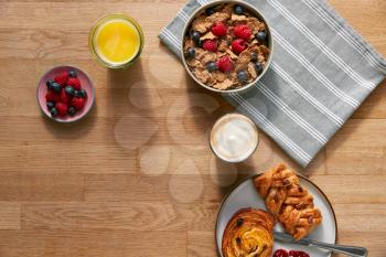 Overhead Flat Lay Shot Of Table Laid For Breakfast With Cereal Pastries And Coffee