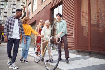 Group Of Multi-Cultural Friends Walking On City Street With Sustainable Bamboo Bicycle