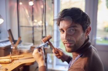 Portrait Of Smiling Male Jeweller At Bench Working In Studio