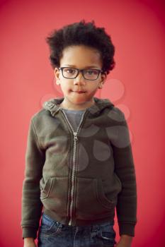 Portrait Of Young Boy Wearing Glasses Against Red Studio Background